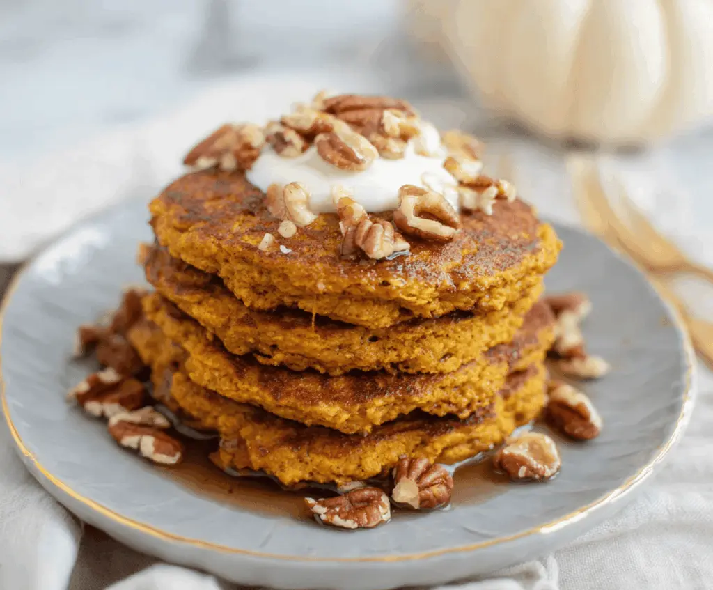 Creamy Blender Pumpkin Oatmeal Pancakes topped with fresh fruit and maple syrup for a delicious breakfast