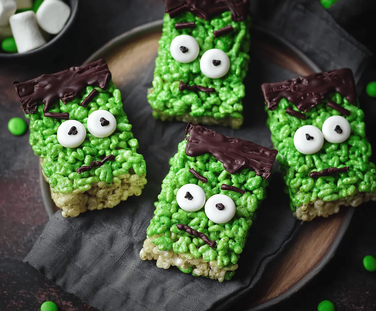 Colorful Frankenstein Rice Krispie Treats with green frosting, candy eyes, and Halloween-themed decorations, perfect for spooky celebrations.