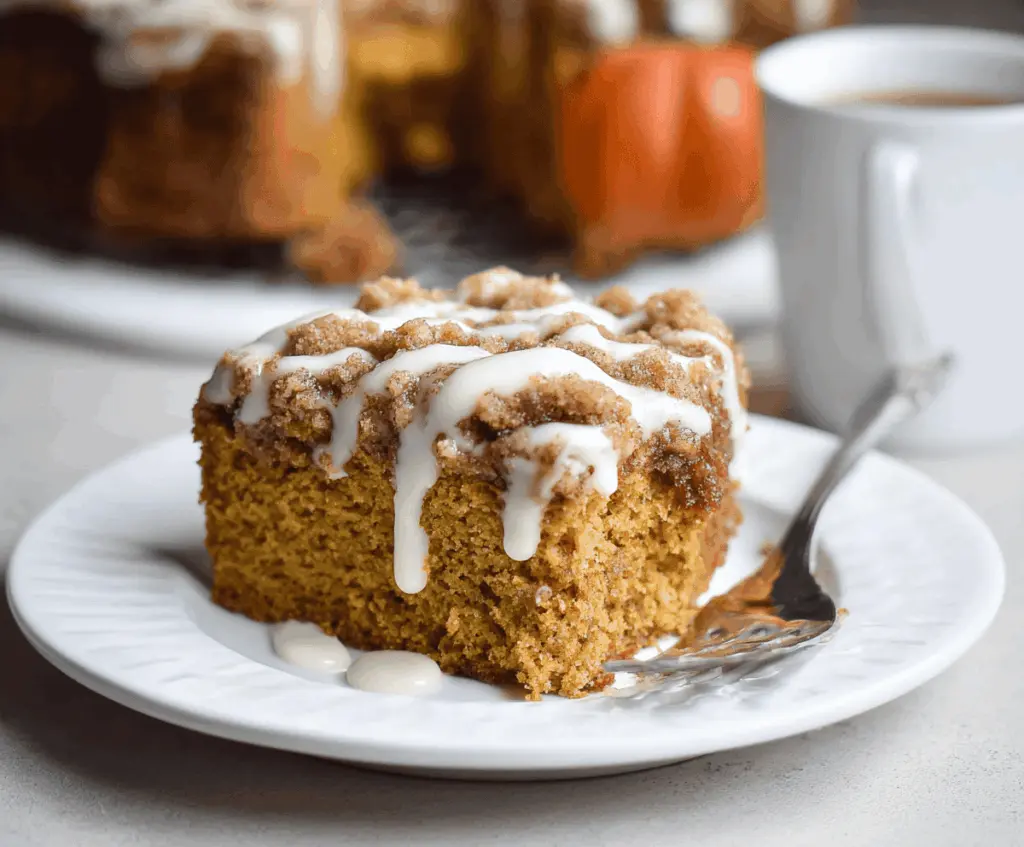 Delicious Pumpkin Cinnamon Coffee Cake topped with cinnamon sugar and served with a slice on a plate