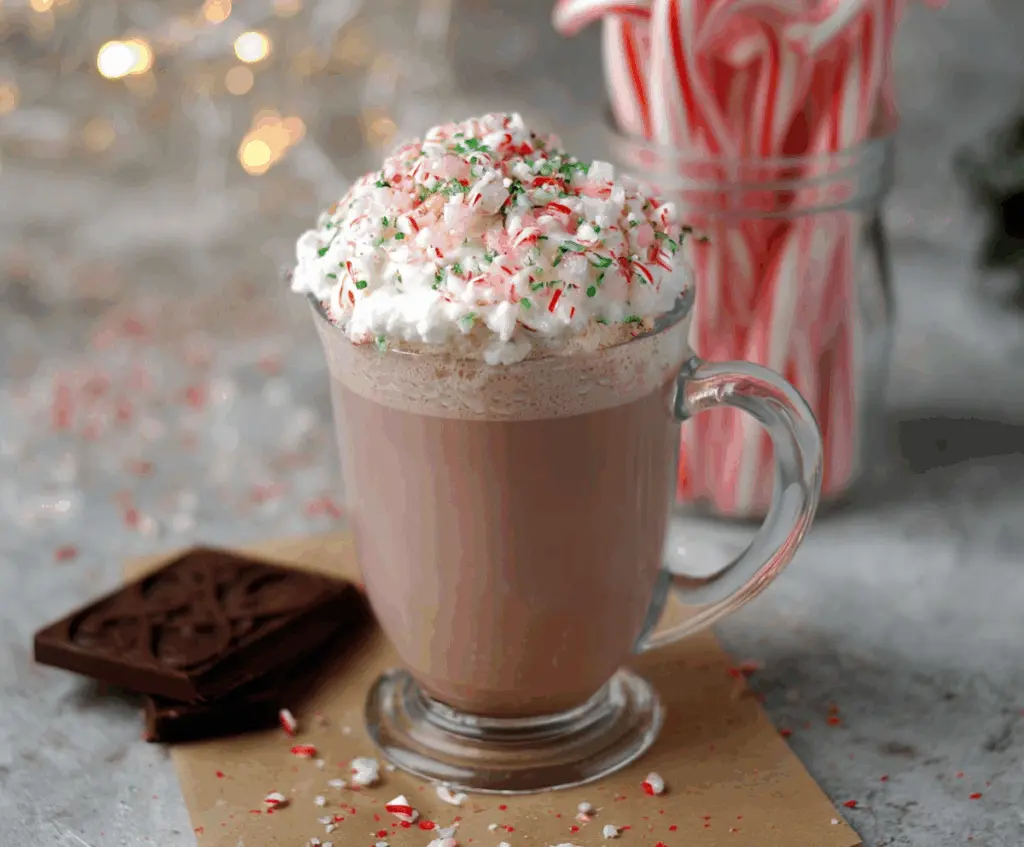 Warm Candy Cane Hot Chocolate in a mug topped with whipped cream and crushed candy canes.