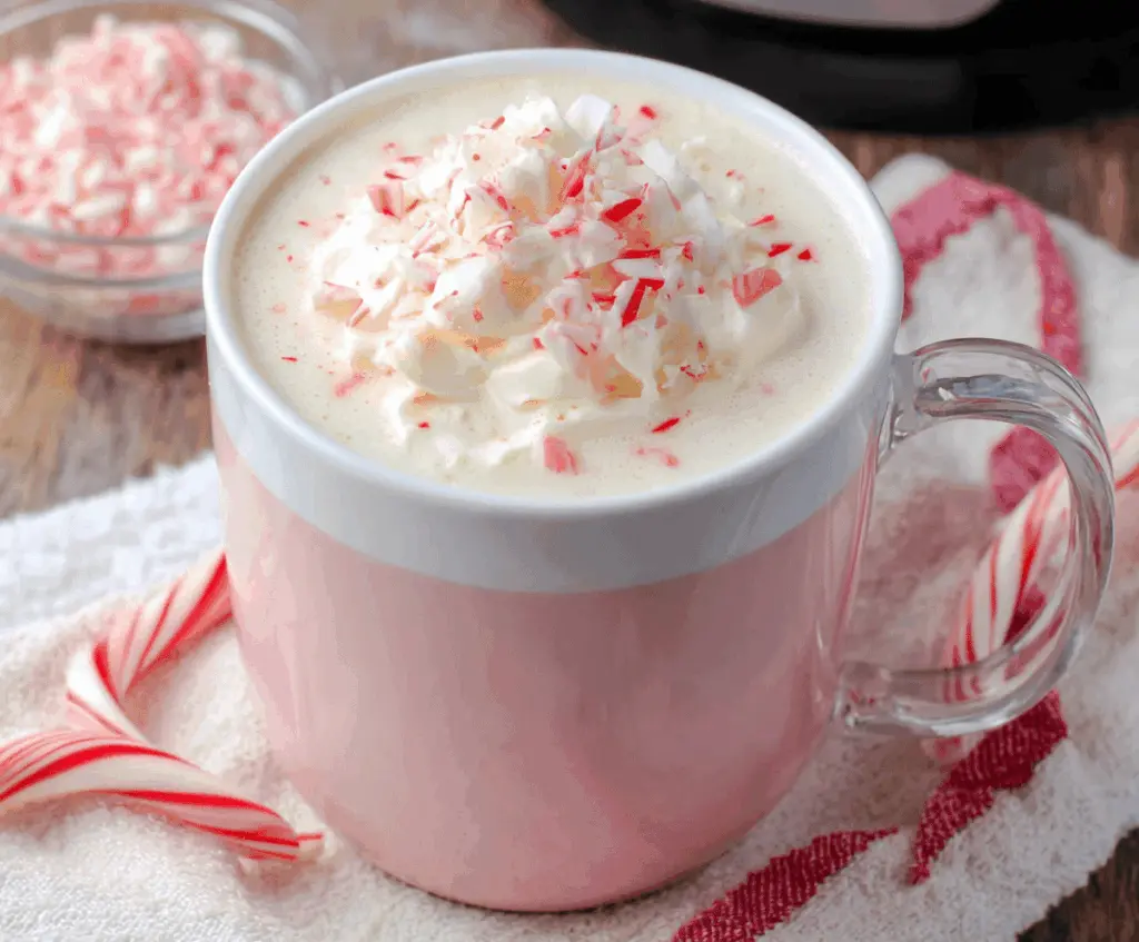 Creamy Crockpot Candy Cane White Hot Chocolate in a festive mug, topped with whipped cream and crushed candy canes.