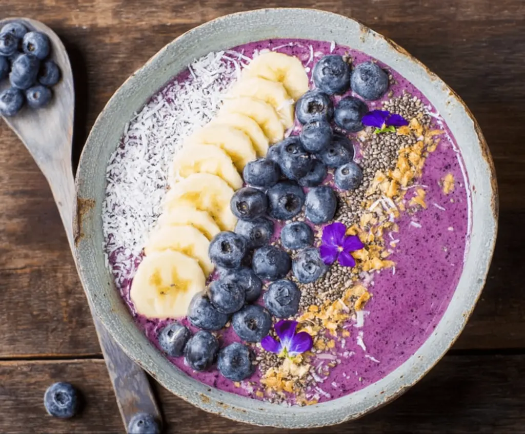 Delicious blueberry smoothie bowl topped with fresh blueberries, granola, and mint leaves for a healthy breakfast.