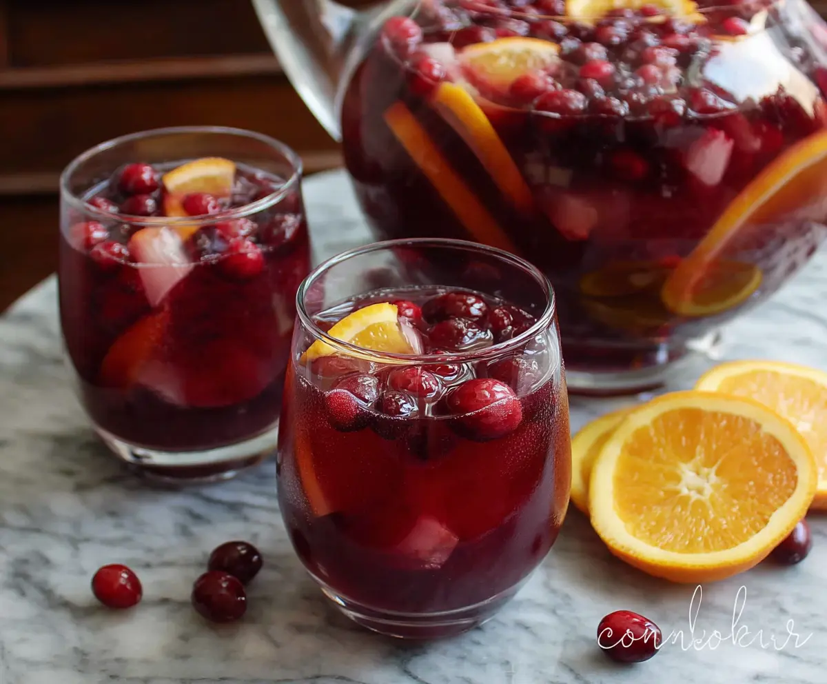 Refreshing Cranberry Sangria in a glass pitcher garnished with fresh cranberries and citrus slices.
