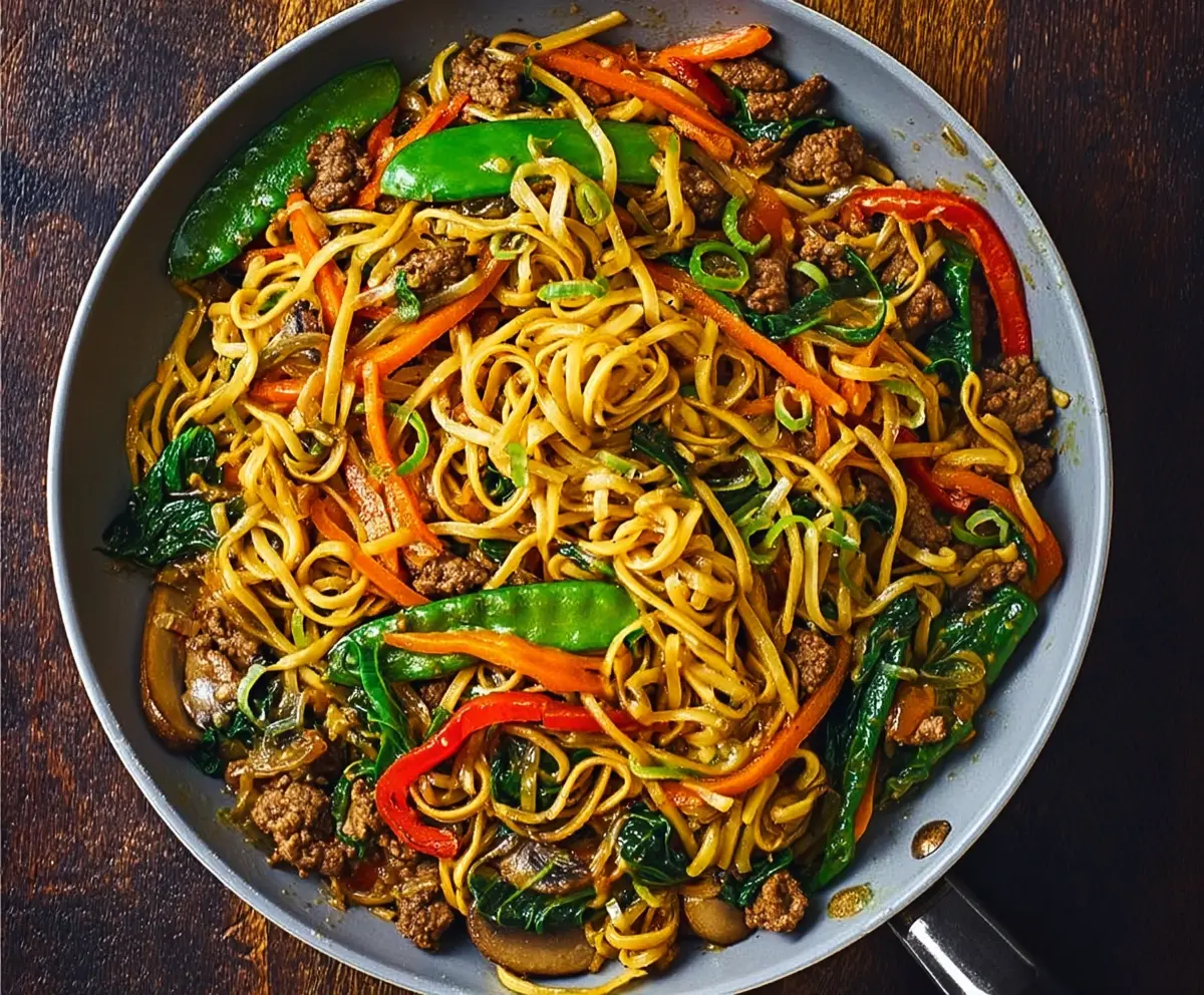 Delicious pork stir fry with colorful vegetables served over noodles.
