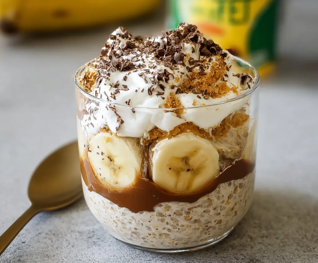 Creamy Banoffee Pie Overnight Oats with bananas, caramel, and crushed biscuits in a glass jar.