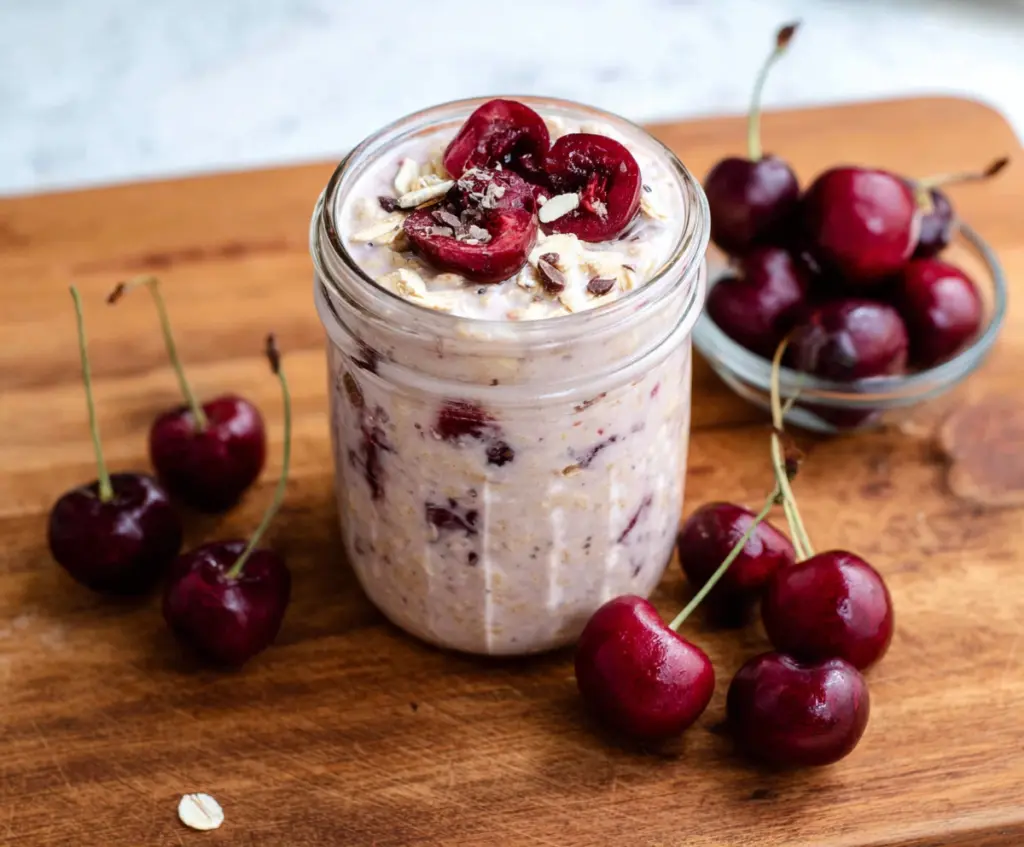 Delicious cherry overnight oats topped with fresh cherries and a sprinkle of chia seeds in a glass jar.