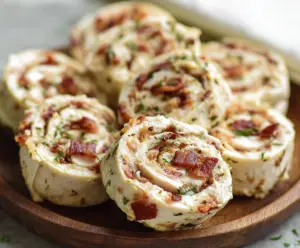 Delicious Chicken Bacon Ranch Pinwheels with crispy bacon and creamy ranch filling on a cutting board.
