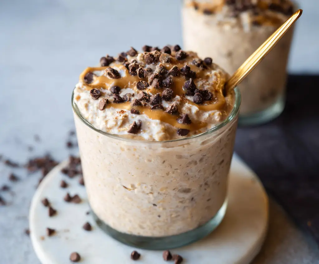 Delicious cookie dough overnight oats in a glass jar topped with chocolate chips and a drizzle of honey.