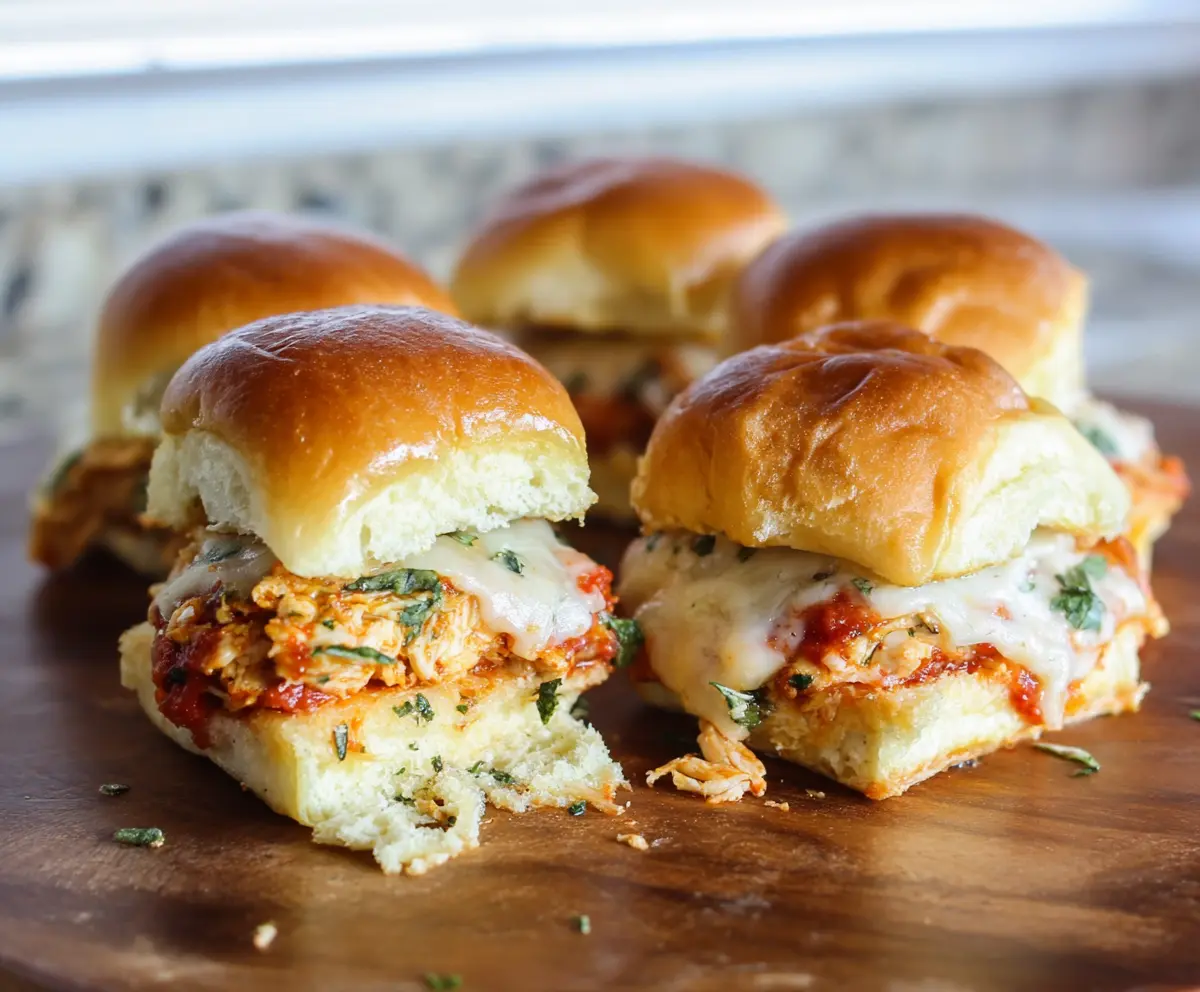 Delicious Garlic Chicken Parmesan Sliders with melted cheese and fresh herbs on a serving platter.