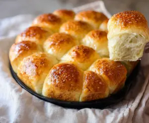 Soft and fluffy pull-apart sourdough dinner rolls served on a rustic wooden table.