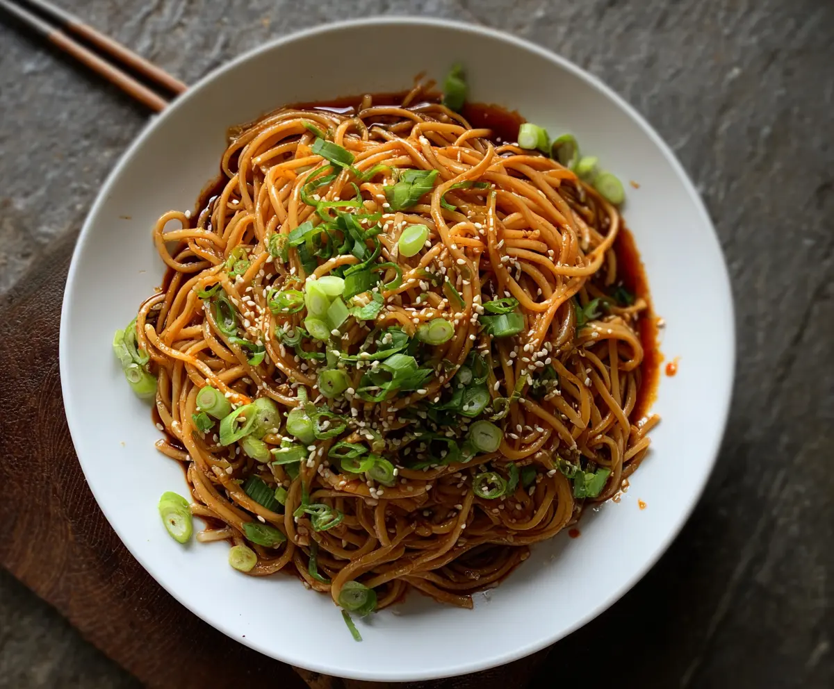 Delicious Cold Spicy Szechuan Sesame Noodles garnished with chopped green onions and sesame seeds.