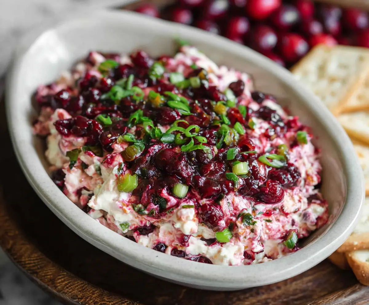 Creamy cranberry jalapeno cream cheese dip garnished with fresh herbs, perfect for appetizers.