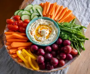 Colorful veggie platter with hummus dip and fresh vegetables for a healthy snack idea.