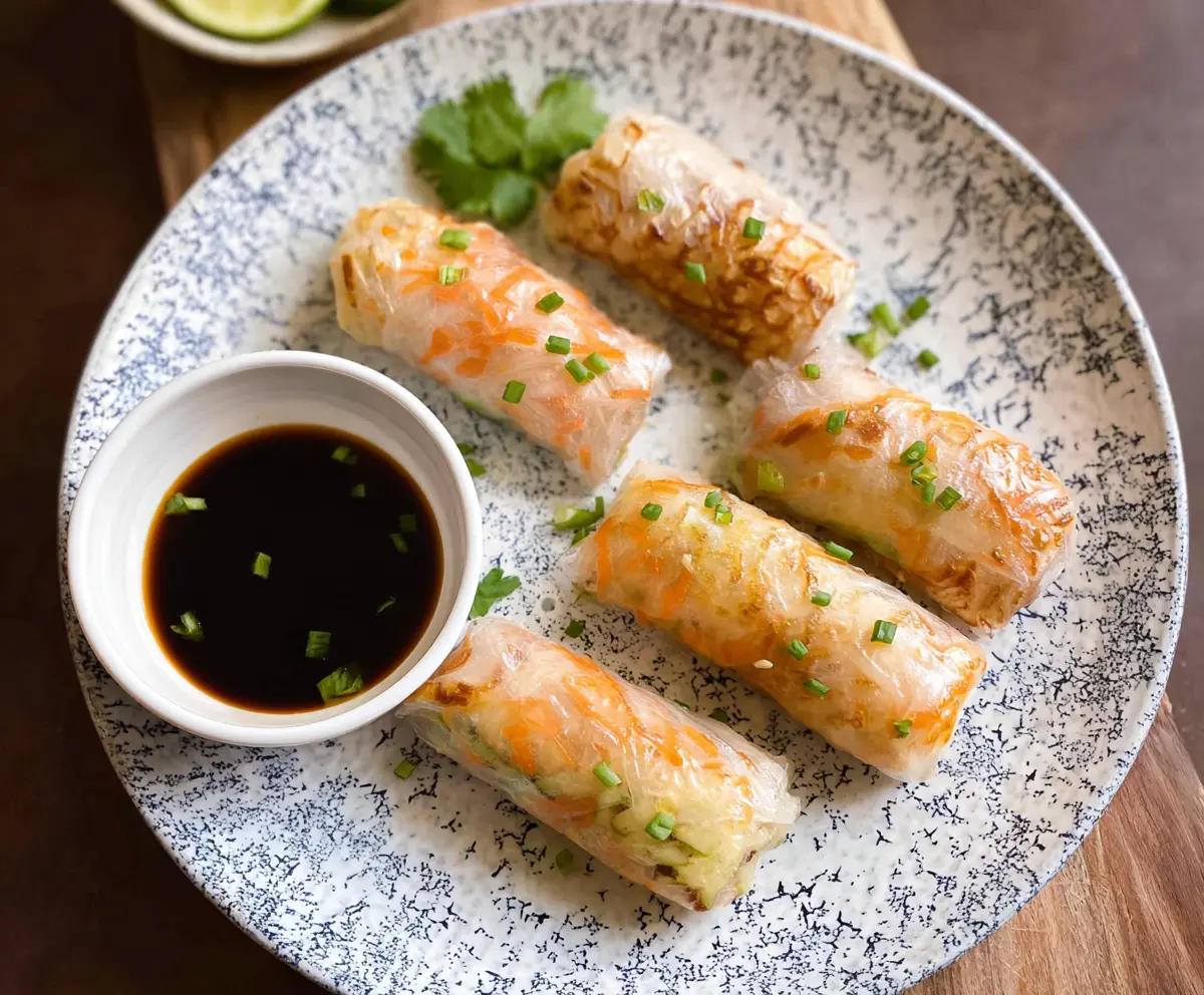 Crispy rice paper rolls filled with fresh vegetables served with dipping sauce in an air fryer.