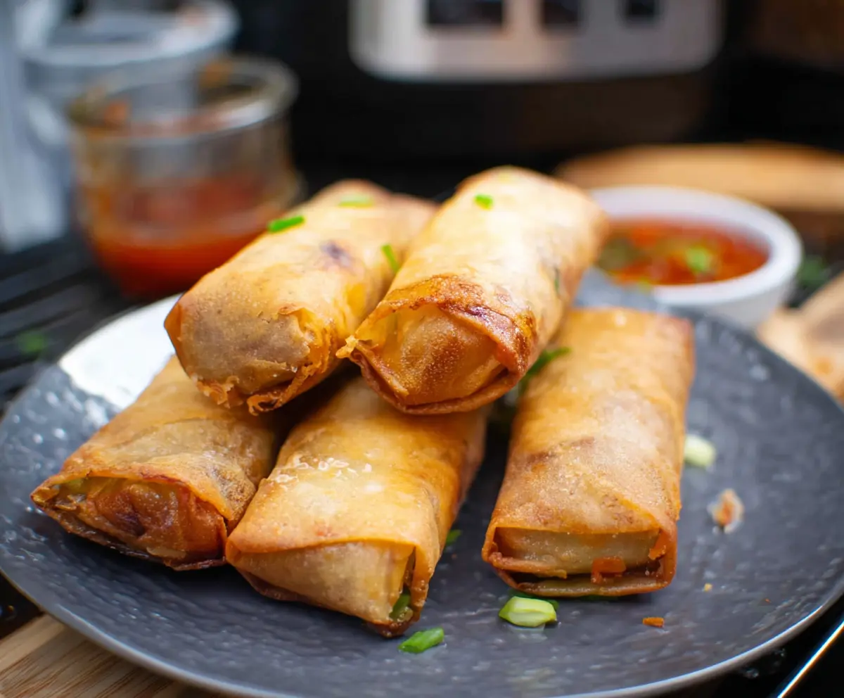 Crispy air fryer spring rolls filled with fresh vegetables served on a white plate.