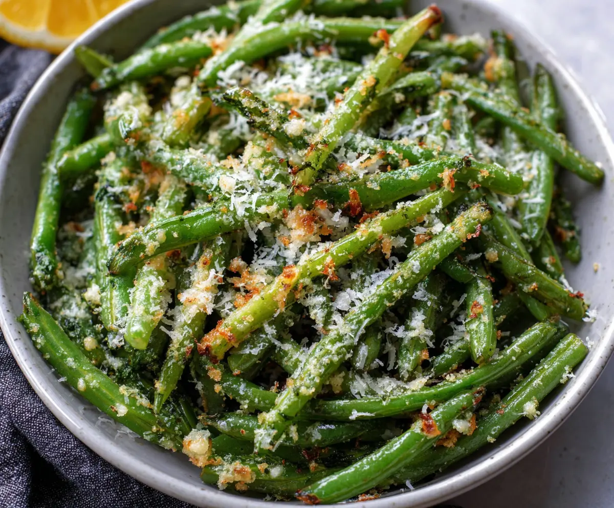 Crispy garlic Parmesan green beans served on a white plate, garnished with fresh herbs