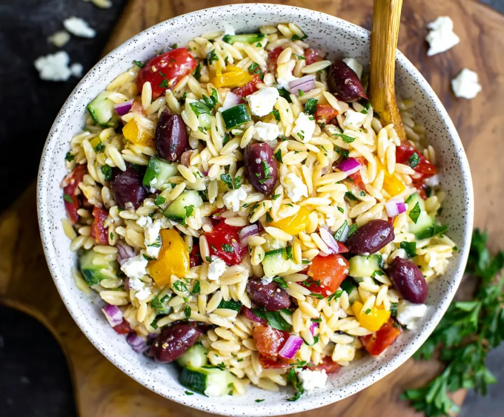 Refreshing Greek Orzo Salad with cucumbers, tomatoes, feta cheese, and herbs in a bowl.
